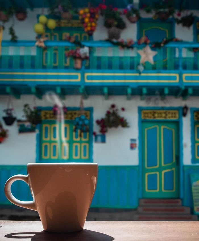 A steaming coffee cup in front of colorful traditional Colombian architecture in Salento., Quindío