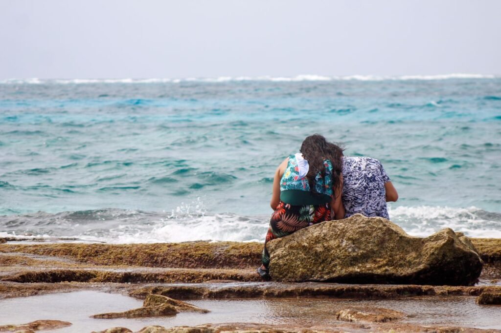 A couple sitting on rocks by the ocean in San Andrés, Colombia, enjoying the view., San Andrés