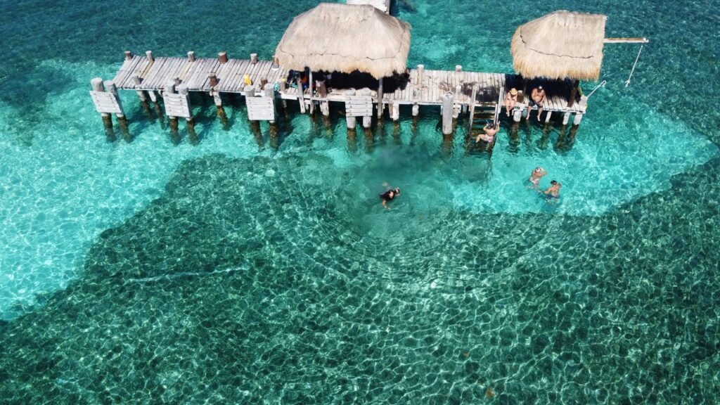 Breathtaking aerial view of Isla Mujeres pier with tourists and clear turquoise waters., Islas de Rosario