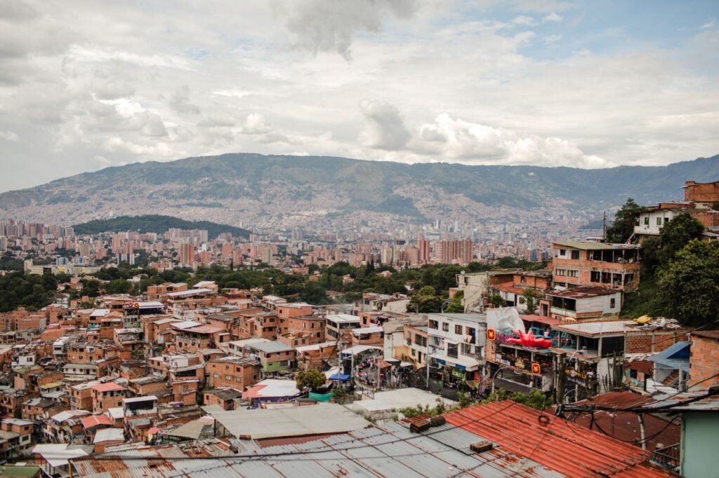 Stunning cityscape of Medellín with vibrant rooftops and distant mountains under a cloudy sky., Medellín