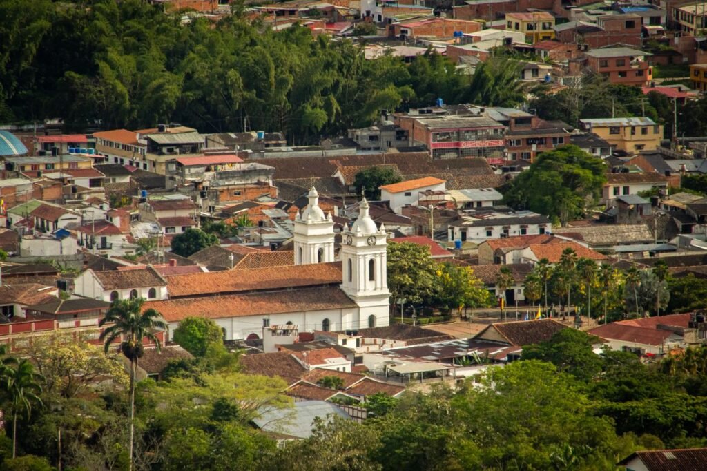Aerial shot of picturesque Salento with the historic church nestled among colorful rooftops and lush greenery., Quindío
