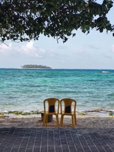 Serene beach scene with two chairs facing turquoise waters of San Andres, Colombia.