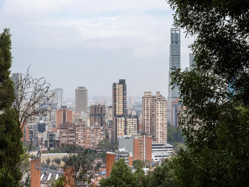 A scenic view of Bogotá's skyline surrounded by greenery, showcasing urban architecture and nature.