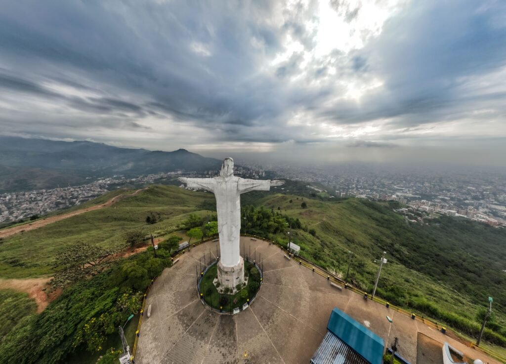 Breathtaking aerial view of the Cristo Rey statue overlooking Cali, Colombia surrounded by lush greenery and urban landscape.