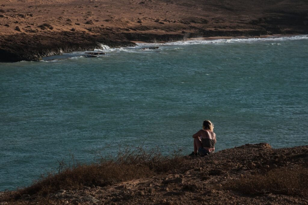 Woman gazes at the ocean from a cliff at Cabo de La Vela, capturing a serene summer moment. La Guajira