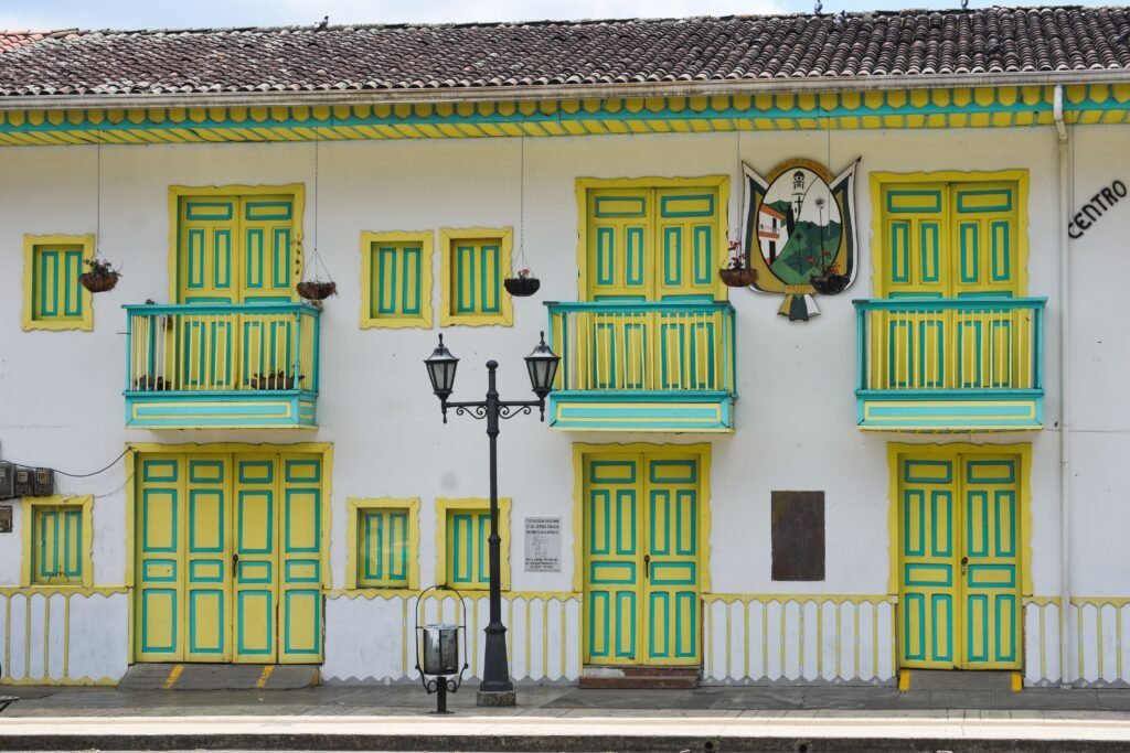 Brightly painted colonial building facade with yellow and green doors and windows in a lively street setting. Colombia 10 días
