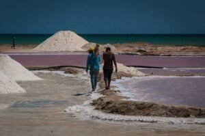 Two men walking through salt evaporation ponds in Manaure, La Guajira, Colombia on a sunny day.