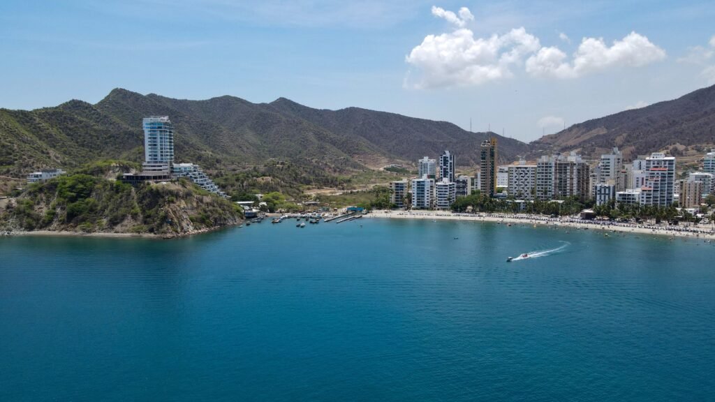 A vibrant coastal city with mountains, beach, and clear blue sea under a sunny sky. paquetes santa marta todo incluido