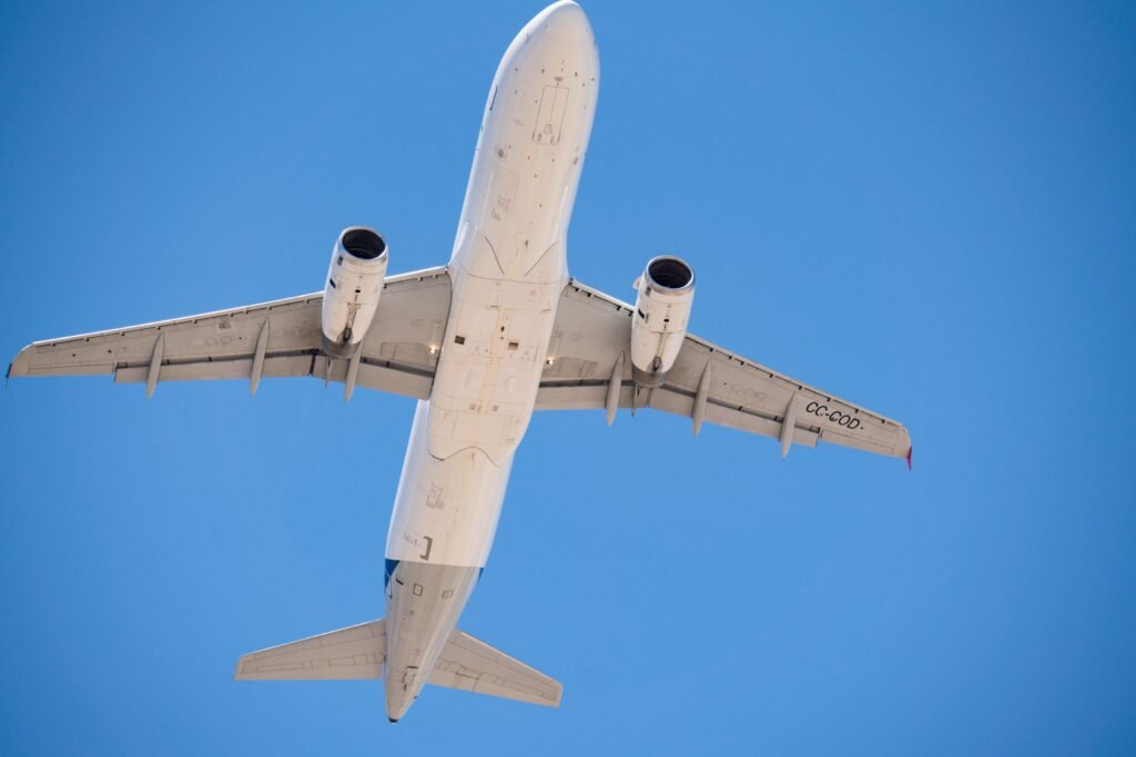 A commercial airplane flying overhead with a clear blue sky in Santiago, Chile. consejos para conseguir vuelos baratos