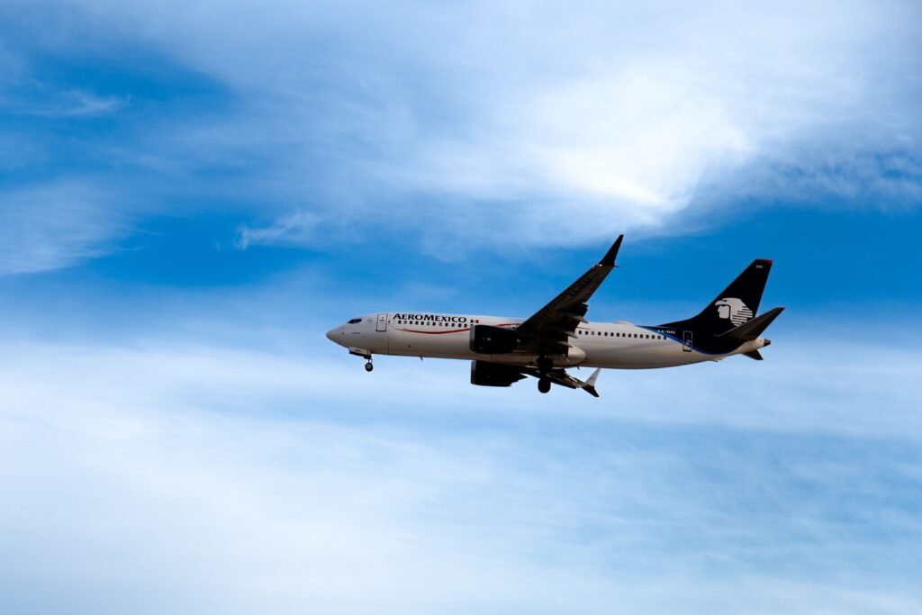 Aeromexico commercial airplane flying midair with a blue sky backdrop, showcasing travel and transportation. consejos para conseguir vuelos baratos
