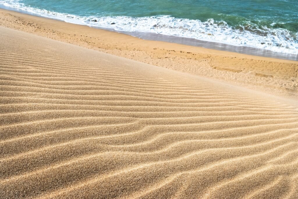 Golden sand ripples leading to turquoise waves at La Guajira beach, Colombia. La Guajira