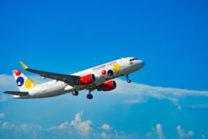 Airplane in flight over Colombia's blue skies, showcasing vibrant branding.