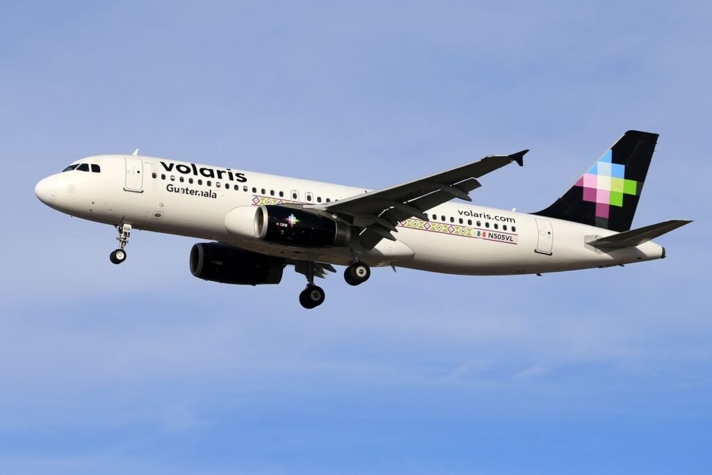 Volaris airplane in flight against clear blue sky, showcasing modern aviation. consejos para conseguir vuelos baratos