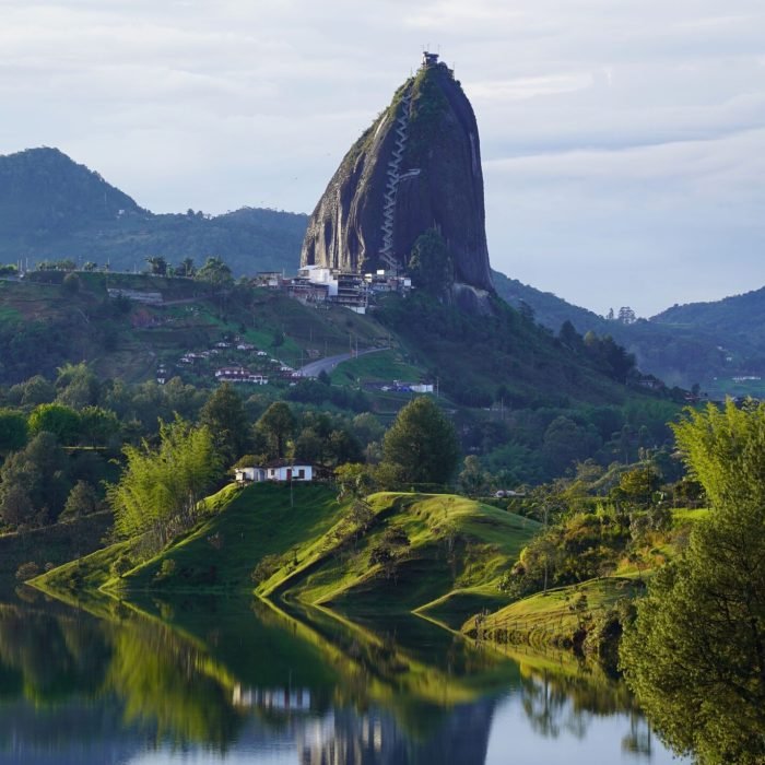 A tranquil lake nestled in front of majestic mountains and lush green trees. Guatape, Colombia.